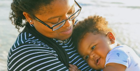 Young mother smiling and holding baby.